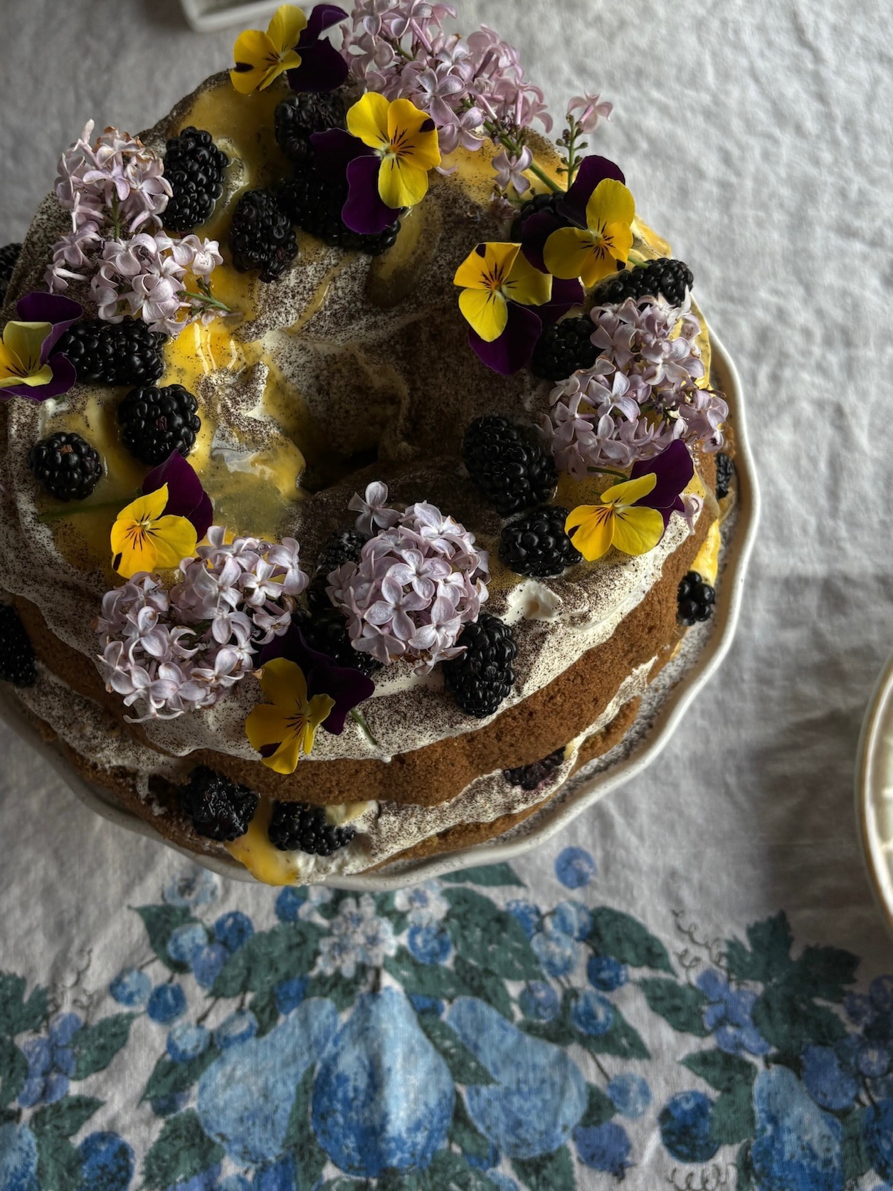 Naked cake with lilac blossoms, blackberries and lemon curd, top view